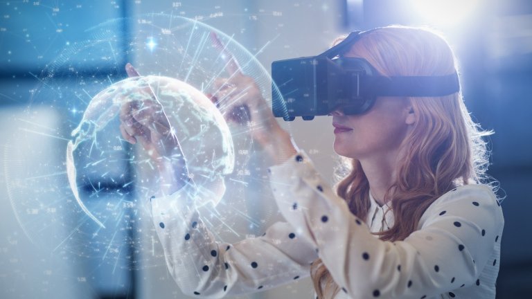 Frau mit VR-Brille bewegt mit ihren Fingern eine virtuelle Kugel