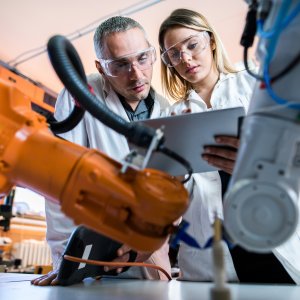 Forscher im Labor vor Roboterarmen
